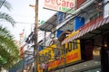 An installer in Thailand standing on scaffolding installs a sign on the facade of a building