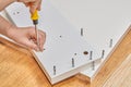 Installer uses cam lock screws as fasteners for flat-pack furniture.