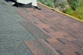 Installing asphalt roof shingles on the underlayment of the house construction repairing the rooftop in chimney problem area.