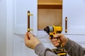 Installing cabinet handles with a power drill in a modern kitchen setting Royalty Free Stock Photo