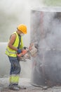 Installing a concrete pipe in the ground to collect rainwater. The worker cuts holes in the concrete part of the pipe to