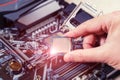 Installing the CPU into a socket on the motherboard. The technician holds the blank central processing unit of the PC