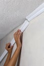 Installing crown molding on ceiling in room with painted wall. Fragment of molding, horizontal view.