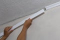 Installing crown molding on ceiling in room with painted wall. Fragment of molding, horizontal view.