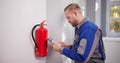 Installing Emergency Fire Extinguisher To Ensure Workplace Security Royalty Free Stock Photo