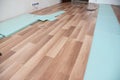 Installing wooden laminate flooring with insulation and soundproofing sheets. Royalty Free Stock Photo