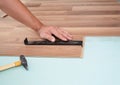 Installing laminate flooring. Man Installing New Laminate Wood Flooring. Worker Installing wooden laminate flooring with hammer. Royalty Free Stock Photo