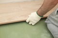 Installing laminate or parquet floor in room, detail on man hands fitting wooden tile, over green foam base Royalty Free Stock Photo