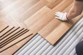 Installing laminated floor, detail on man hand in white glove fitting wooden tile, over white foam base layer Royalty Free Stock Photo