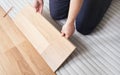 Installing laminated floor, detail on man hands fitting wooden tile, over white foam base layer Royalty Free Stock Photo