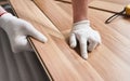Installing laminated floor, detail on man hands in white gloves positioning wooden tile, over white foam base layer Royalty Free Stock Photo