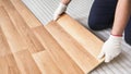 Installing laminated floor, detail on worker hands in white gloves fitting wooden tile, over white foam base layer Royalty Free Stock Photo