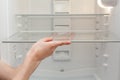 Installing new, clean shelves in an empty washed refrigerator. Young woman cleaning refrigerator