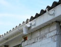 Installing plastic roof gutter holder for dowspout drain pipe outdoor. Plastic roof guttering, rain guttering