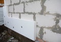 Installing rigid foam board insulation using screws with large washers on the house wall made from large concrete blocks