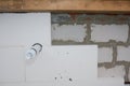 Installing rigid polystyrene foam board insulation with adhesive or glue on a brick wall with a ventilation pipe