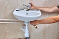 Installing single lever faucet on washroom sink, plumber inserts water tap into washbasin hole.