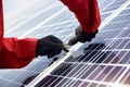 Installing solar panels. Close-up of mans hands in orange uniform and black gloves with wrench in his hands