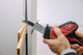 Installing a wooden beam cased opening walkway between rooms, closeup hand of woodworker with cutting tool hackzall cut wooden Royalty Free Stock Photo