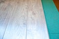 Installing wooden laminate or parquet floor in room over green noise absorbing base, close-up