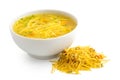 Instant chicken noodle soup in a white ceramic bowl next to a pile of dry instant soup isolated on white