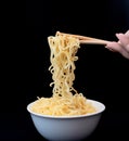 Instant Chinese curly noodles in white bowl with wood sticks on black background. Selective focus. Asian food concept Royalty Free Stock Photo