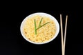 Instant Chinese curly noodles in white bowl with wood sticks on black background. Selective focus. Asian food concept Royalty Free Stock Photo