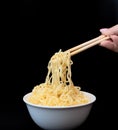 Instant Chinese curly noodles in white bowl with wood sticks on black background. Selective focus. Asian food concept Royalty Free Stock Photo