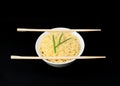 Instant Chinese curly noodles in white bowl with wood sticks on black background. Selective focus. Asian food concept Royalty Free Stock Photo