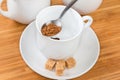 Instant coffee granules in spoon atop empty cup on saucer