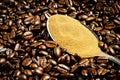 Instant coffee in spoon on coffee beans background