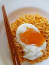 Instant Noodle with boiled egg in white plate and brown chopstick