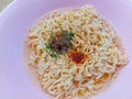 Instant noodle in a pink bowl with some seasoning ingredient