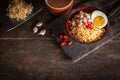 Instant noodle with pork, egg and vegetables on black bowl on the wood table there are chilli, chopstick, garlic, instant noodle Royalty Free Stock Photo