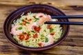 Instant noodle with shrimps, red pepper and green onion in a ceramic bowl. Japanese food. Chopsticks with shrimp