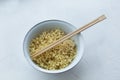 Instant noodles in a bowl with wooden chopsticks on a white textured background Royalty Free Stock Photo