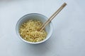 Instant noodles in a bowl with wooden chopsticks on a white textured background Royalty Free Stock Photo