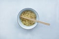 Instant noodles in a bowl with wooden chopsticks on a white textured background Royalty Free Stock Photo