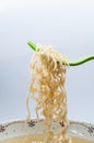 Instant noodles with green fork on white background