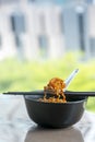 Instant noodles korean hot chili ramen stlye with pork cracklink chilli paste in black bowl with chopstick