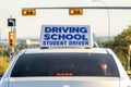 An instructional vehicle, bearing a prominent driving school student driver sign