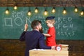 Instructive conversation concept. Teacher with beard, father teaches little son in classroom, chalkboard on background