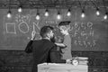 Instructive conversation concept. Teacher with beard, father teaches little son in classroom, chalkboard on background Royalty Free Stock Photo