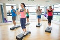 Instructor with fitness class performing step aerobics exercise with dumbbells Royalty Free Stock Photo