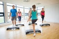 Instructor with fitness class performing step aerobics exercise Royalty Free Stock Photo