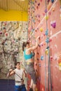 Instructor guiding woman on rock climbing wall Royalty Free Stock Photo