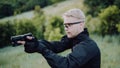 Instructor with gun in forest leads aiming and posing on camera Royalty Free Stock Photo