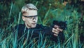 Instructor with gun in forest leads aiming and posing on camera Royalty Free Stock Photo