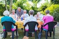 Instructor helping a group of senior retired ladies at art class seated around a table painting outdoors in a garden or park. Royalty Free Stock Photo