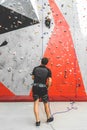 The instructor insures the child. Kid climber moving up on steep rock, climbing on artificial wall indoors. Extreme